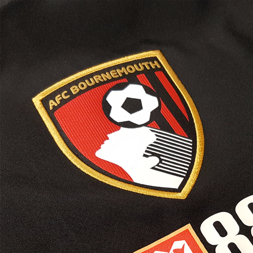 AFC Bournemouth woven badge with embroidered gold stitching.on black trainingwear garment.
